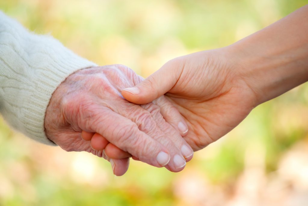 Senior and young person holding hands